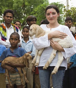 Volunteer poses with lamb and children